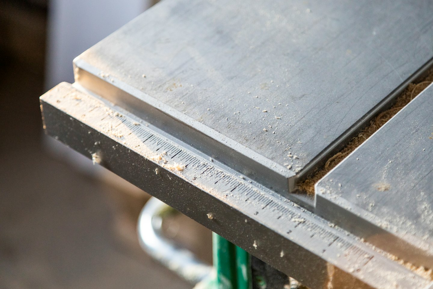 Fine sawdust covers the metal surface of a table saw.