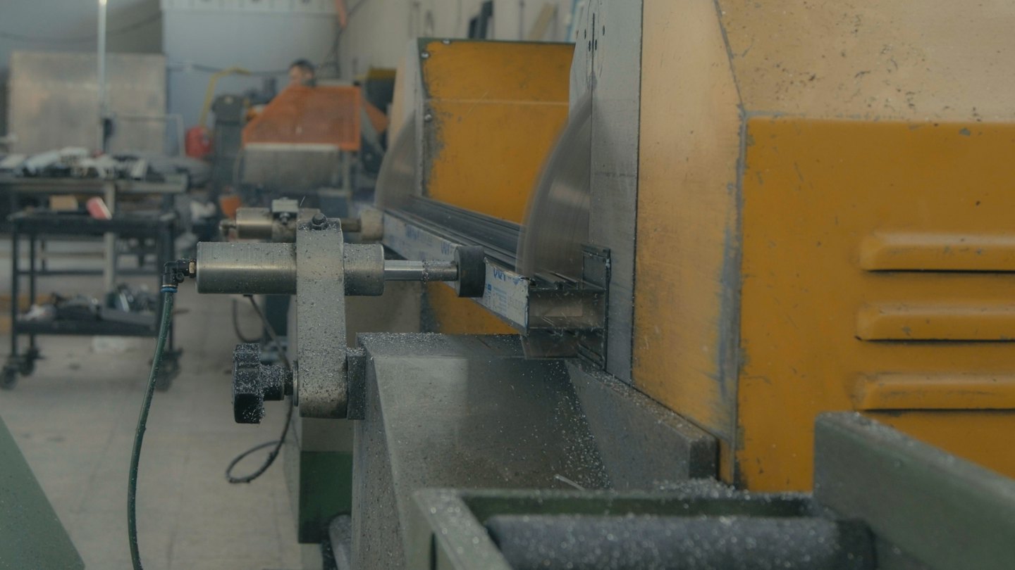 Industrial cutting machine with circular saws cuts metal profile.
